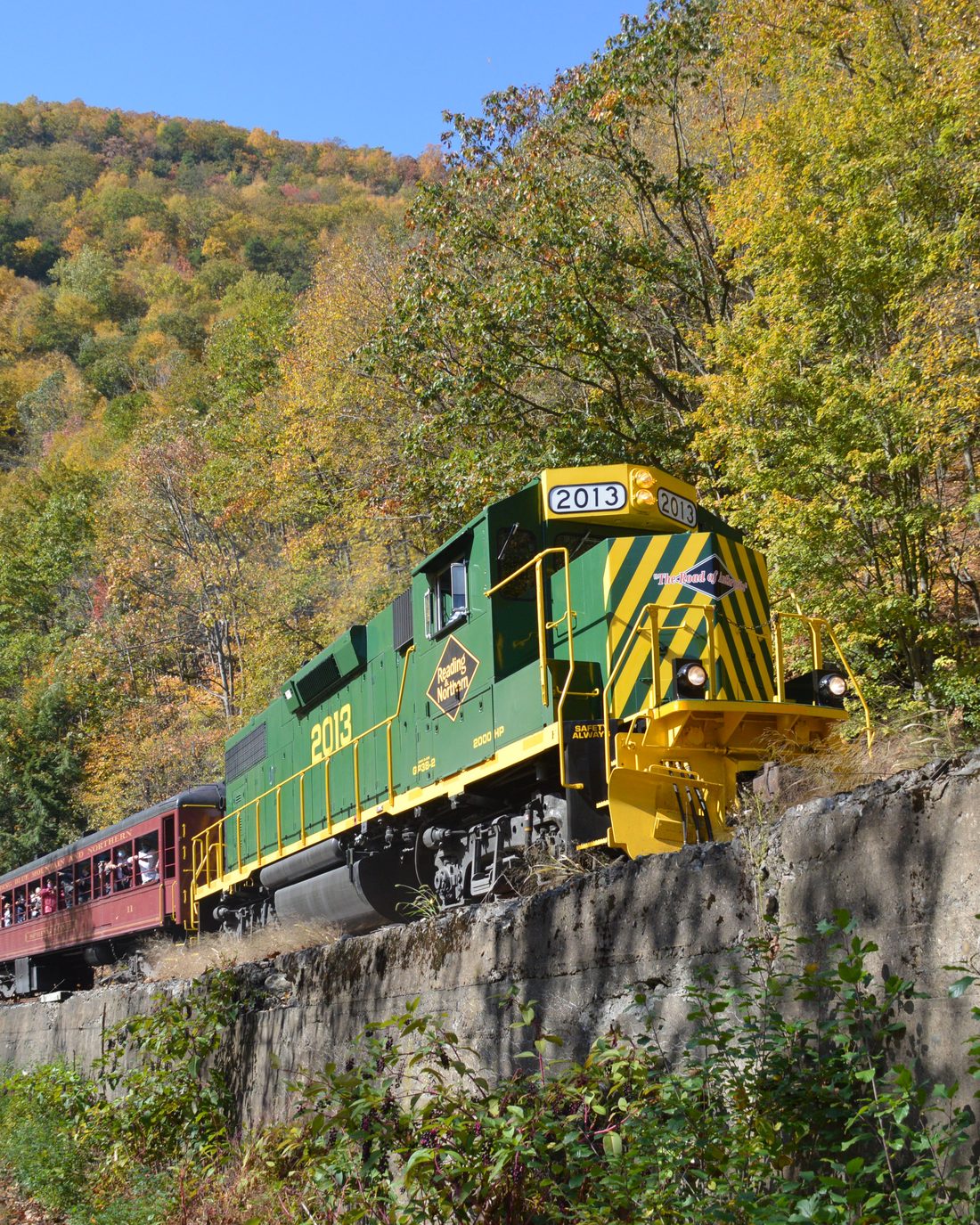 The Lehigh Gorge Scenic Railway train pulling passenger cars past autumn foliage near Jim Thorpe, Pennsylvania